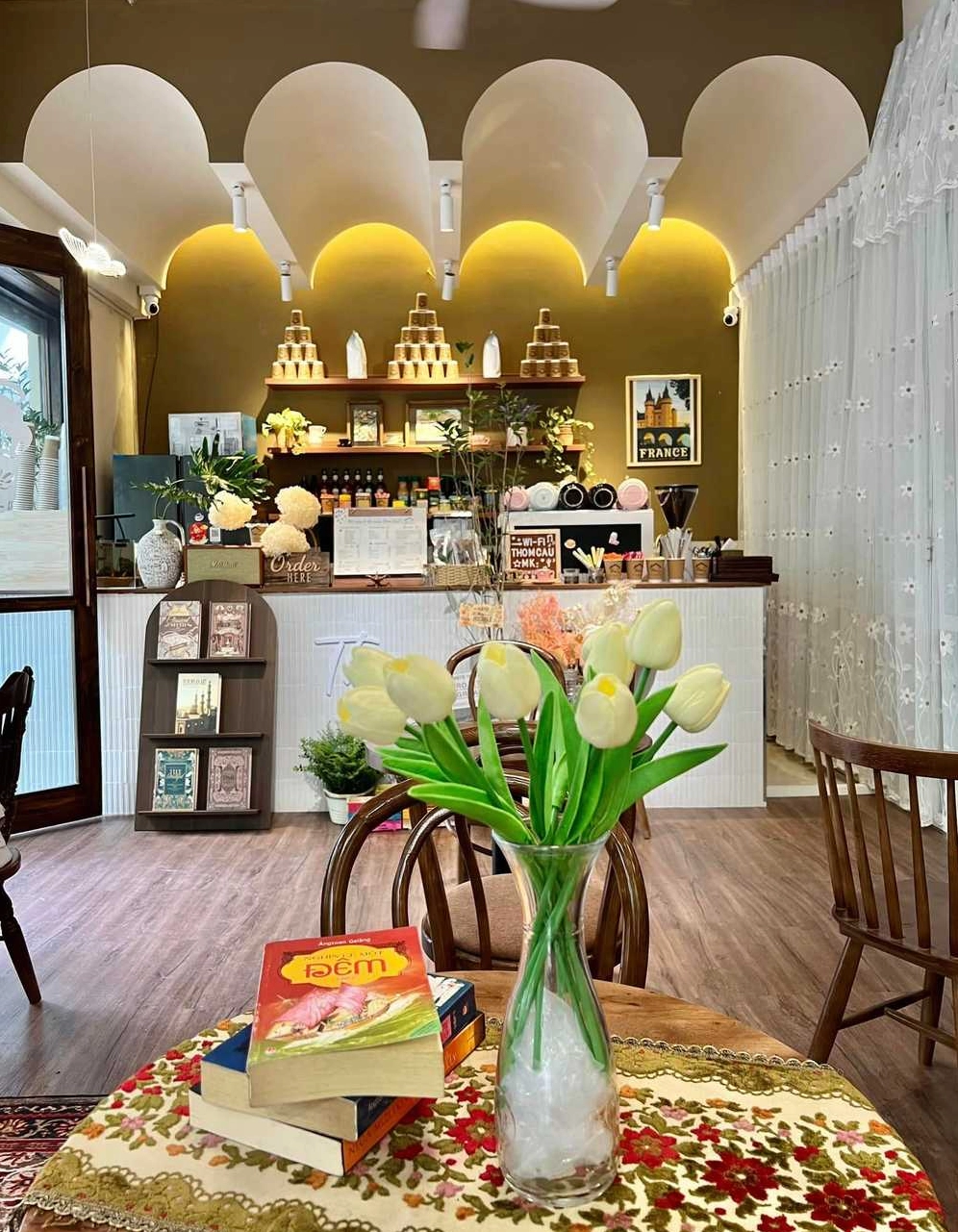 Bàn làm việc cạnh cửa sổ tại Thom Cau Coffee, nơi ánh sáng tự nhiên tràn ngập, lý tưởng để làm việc hoặc đọc sách.